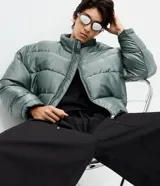 Campera puffer Blue Steel de poliamida con efecto metalizado color verde, cuello alto, cierre frontal por cremallera y bolsillos laterales.