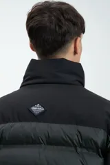 Campera puffer negra y beige con cierre frontal y cuello alto. Estampado con la marca "Unfrm" en el pecho.