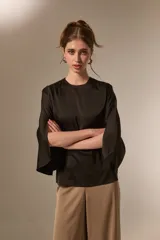 Blusa de satén color negro, con cuello redondo a la base, mangas 3/4 con abertura lateral y diseño holgado.