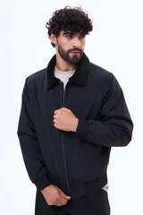 Campera de nylon color negro con cierre frontal, puños y ruedo elásticos, y cuello con forro de corderito sintético.