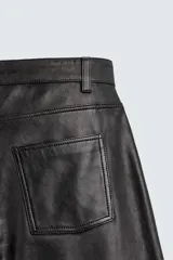 Pantalón slim fit confeccionado en piel, con diseño de cinco bolsillos, cierre frontal de cremallera y botón.