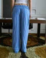 Pantalón de poplin de algodón a rayas verticales celestes y blancas, con cintura elástica y bolsillos traseros.