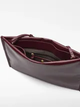 Bolso tipo clutch de Adolfo Dominguez en color bordó con acabado brillante y textura craquelada. Cuenta con un compartimento principal con cierre magnético, bolsillo interior con cremallera, asa de mano integrada y asa larga regulable y extraíble.