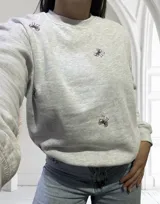 Buzo gris con estampado de moños rosas.