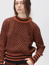 Sweater de tejido de punto jacquard con diseño geométrico, cuello redondo y puños acanalados en contraste de color verde y beige.