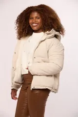 Campera reversible para dama con un lado de nylon acolchado y el otro de corderito sintético. Cuenta con capucha, cierre frontal y bolsillos laterales.