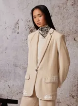 Blazer color beige de terciopelo, con solapas y bolsillos delanteros con detalle de tachas.