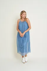 Vestido largo celeste de seda natural, con breteles finos y escote redondo con detalle de flecos largos.