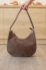 Cartera hobo de cuero color rojo con silueta curva de media luna, cierre superior y correa de hombro ajustable.