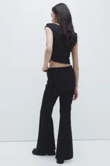 Pantalón acampanado de tiro alto con pollera mini superpuesta integrada, cierre frontal y botón.