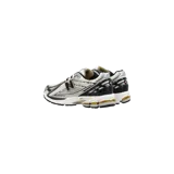 Championes New Balance modelo 1906R, color blanco con detalles plateados, negros y dorados, con diseño técnico de malla y superposiciones sintéticas, y tecnología de amortiguación N-ergy.