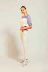 Pantalón de jean blanco de corte chupín, con diseño clásico de cinco bolsillos y cierre frontal con botón y cremallera.