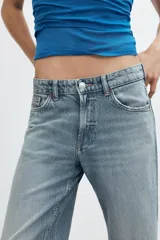 Jeans de denim de tiro medio y corte relaxed con diseño de cinco bolsillos, trabillas en la cintura y cierre frontal con cremallera y botón metálico.