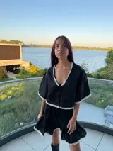 Top de lino con silueta relajada, escote en V y cierre frontal con botones. Presenta detalles de puntilla blanca en el escote, ruedo y mangas.