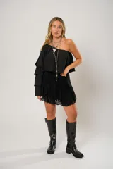 Blusa negra con un hombro descubierto y manga larga con volados.