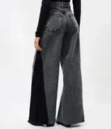 Pantalón wide leg de jean azul con diseño de recorte lateral en tono contrastante. Presenta cintura mediana con trabillas, cierre tradicional y bolsillos funcionales.