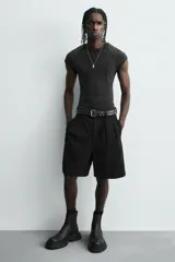 Bota tipo Chelsea de caña media, confeccionada en material sintético liso color negro. Presenta paneles elásticos laterales, tirador trasero y una suela robusta con plataforma track de gran volumen.