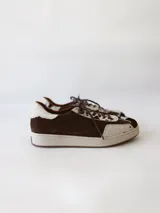 Zapatilla deportiva de cuero con estampado de vaca (pelo), color marrón y blanco. Suela blanca gruesa.