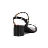 Sandalia de mujer Vizzano color blanco, con acabado charol brillante. Presenta una tira ancha sobre los dedos y una tira fina ajustable con hebilla dorada alrededor del tobillo. Posee un taco ancho y bajo.