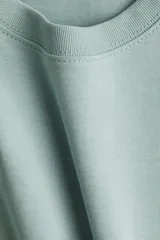 Remera color verde agua, de corte cuadrado y holgado, con cuello redondo y mangas cortas anchas.