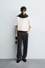 Camiseta blanca de corte holgado, cuello redondo y manga corta. Presenta un parche bordado en la espalda con diseño a contraste.