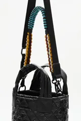 Cartera tote mini negra, con diseño matelasse y dos asas cortas. Incluye una correa larga ajustable y extraíble, con detalles de cuentas de colores.