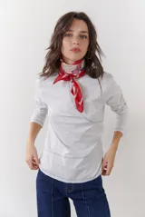 Remera blanca de manga larga con cuello redondo y costuras decorativas en color oscuro.