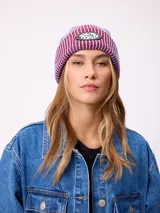 Gorro tipo beanie de tejido acanalado con diseño a rayas verticales en tonos azul y bordó. Presenta un parche ovalado con el logo de la marca Rusty en el frente.
