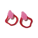 Par de aros colgantes con forma abstracta, con pieza superior rosa y aro inferior rojo.