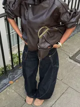 Chaqueta de efecto cuero con cuello alto, cierre frontal cruzado con botones a presión, hombreras y cintura elástica. Presenta un acabado texturizado y bolsillos laterales.
