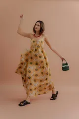 Vestido largo de tirantes finos, con escote en V y estampado de girasoles sobre fondo beige.