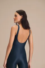 Jumpsuit largo de diseño ajustado con escote redondo y espalda descubierta, confeccionado en tejido satinado con textura acanalada. Presenta copas extraíbles y tecnología de compresión media que se adapta al cuerpo.