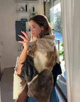 Ruana artesanal confeccionada con piezas de napalán unidas mediante costuras de crochet. Presenta un diseño de patchwork en tonos tierra, marrones y crema, con capucha integrada.