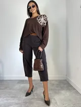 Sweater de punto oversized color verde, con escote en V y manga larga. Presenta un aplique bordado en forma de flor en el hombro izquierdo.