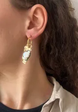 Aros tipo argolla con dije de bronce reticulado de forma irregular y piedra engarzada en el centro. Diseño artesanal con acabado texturizado.