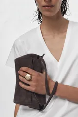 Mini bolso de mano confeccionado en piel, con asa corta, cierre de cremallera y solapa superior. Cuenta con bolsillos exteriores en la parte delantera y trasera, y un bolsillo interior con cierre.