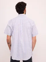 Camisa de manga corta con estampado de cuadros en tonos azul, rojo y beige, confeccionada en algodón. Presenta cuello clásico y cierre frontal con botones.