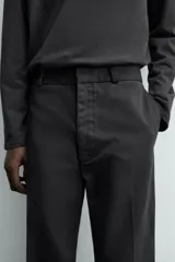 Pantalón chino de corte oversized confeccionado en tejido de algodón con estructura twill. Presenta bolsillos frontales, bolsillos traseros de vivo y cierre frontal con cremallera y gancho metálico oculto.