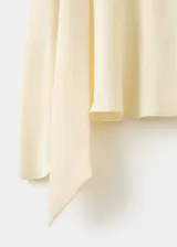 Blusa de manga larga en color crema, confeccionada en poliéster. Presenta un diseño de cuello alto con un sutil detalle de abertura frontal y corte recto.