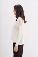 Remera negra de manga larga con detalle de encaje en hombros y espalda.