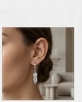 Aros tipo argolla pequeña con dije colgante en forma de pluma con detalle de grabado lineal.
