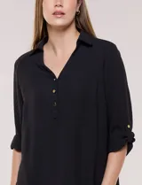 Blusa verde de calce holgado y caída fluida, confeccionada en tejido tipo crepé. Cuenta con cuello camisero con solapa, escote en V y cierre parcial al frente con tres botones metálicos. Las mangas son largas con puños abotonados.
