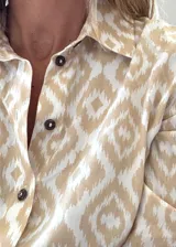 Camisa de fibrana de estilo clásico con estampa ikat en tonos beige y blanco, cuello camisero y botones oscuros.