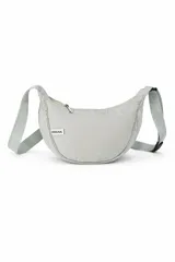 Bandolera color gris claro con forma de media luna, cierre de cremallera y correa ajustable. Incluye etiqueta metálica con el logo de la marca.