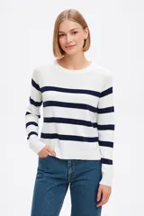 Sweater de punto con diseño de rayas horizontales en azul marino sobre fondo blanco, de corte holgado, cuello redondo y mangas largas con puños acanalados.