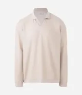 Polo de manga larga color beige claro, confeccionado en tejido texturizado (posiblemente acanalado o waffle). Presenta un cuello polo con escote profundo en V sin botones.
