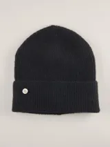 Gorro tipo beanie de punto acanalado en color azul marino, con vuelta y aplique metálico circular con logo de la marca.