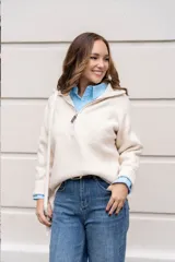 Cardigan de punto color crema, con cuello alto y cierre frontal parcial, de manga larga y diseño holgado.
