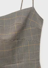 Vestido corto entallado con escote corazón y tirantes finos. Presenta un diseño estampado a cuadros en tonos grises con líneas finas en naranja.