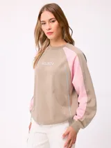 Buzo de cuello redondo con diseño color block, cuerpo en tono crema y mangas negras con detalles de costuras en color bordó. Presenta logo de la marca estampado en el centro del pecho y corte holgado.